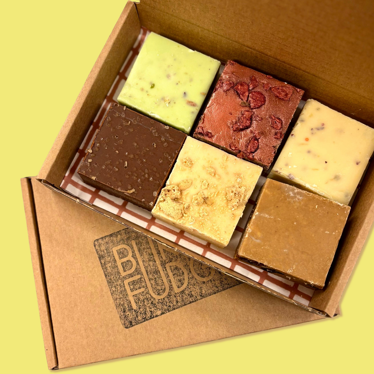 Op de foto staat een open doosje met daarin zes stukken fudge.