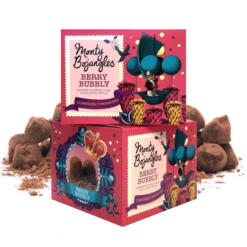 Twee roze doosjes met Monty Bojangles Berry Bubbly staan opgestapeld. Op de achtergrond liggen een aantal chocoladetruffels.