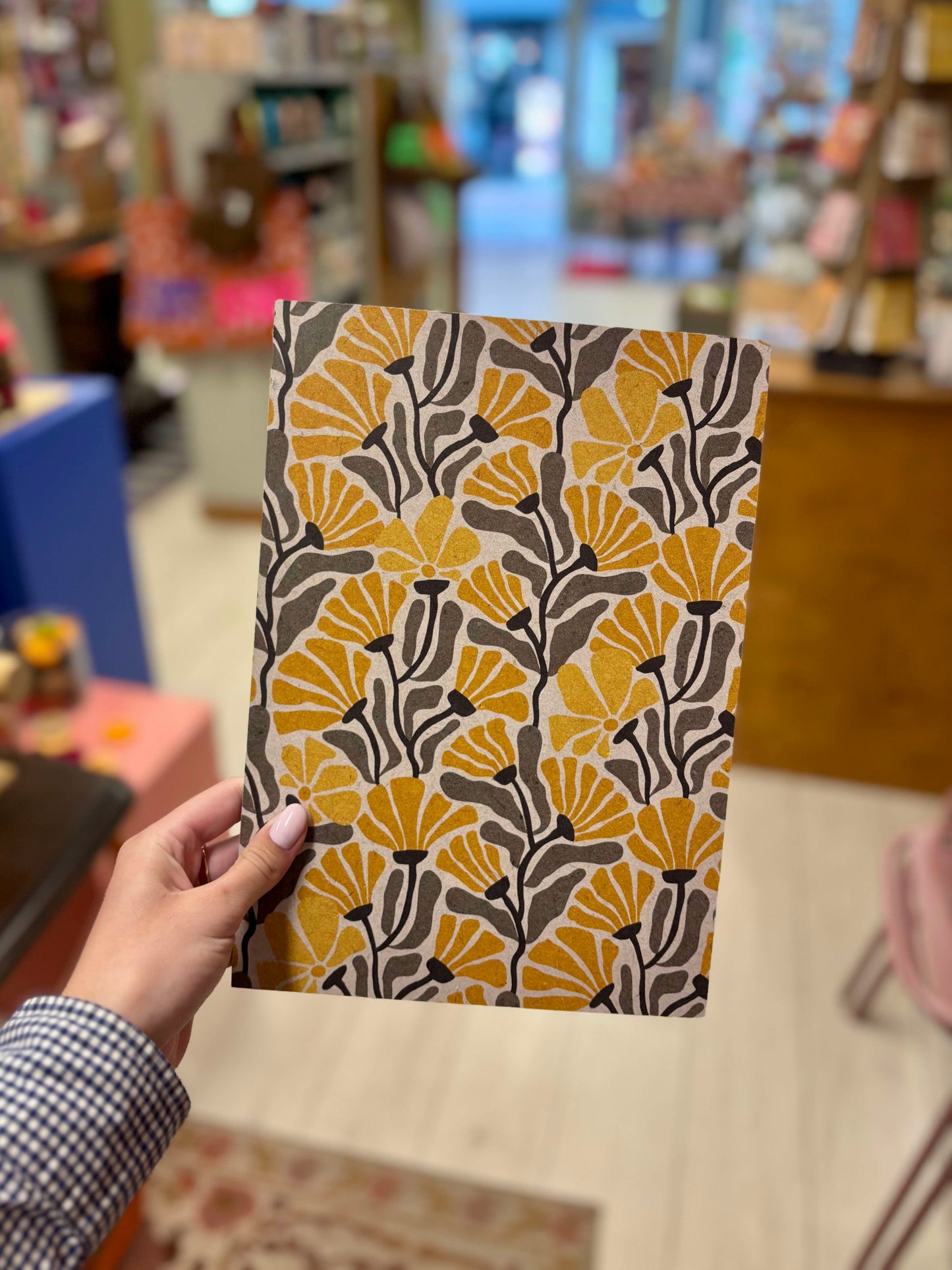 Op de foto zie je een hand die een poster vasthoudt met gele en zwarte bloemen.