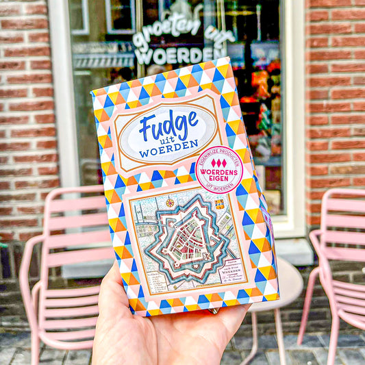 Op de foto zie je een gekleurd doosje met ruitjes erop. Er staat ook een tekst op met 'Fudge uit Woerden'.