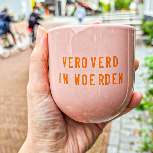 een hand die een roze mok met de opdruk 'veroverd in Woerden' vasthoudt